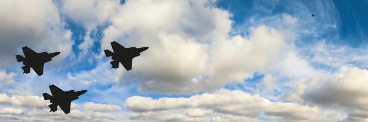 Silhouette von drei Kampfjets vor Wolken am Himmel